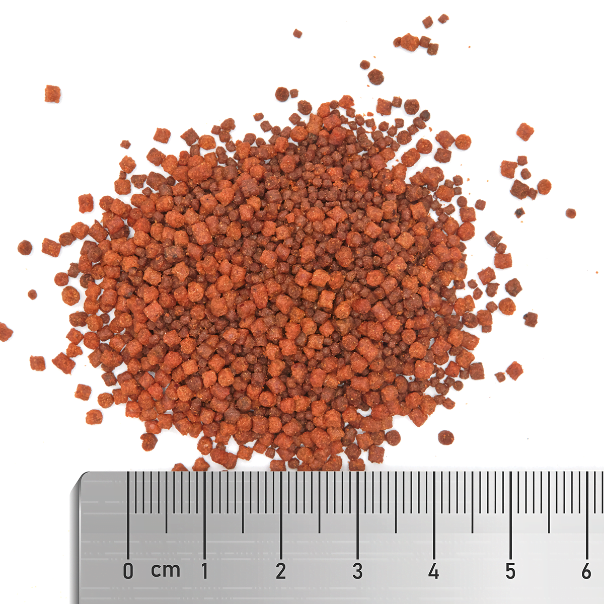 The Fauna Marin Soft Multi Mix from EasternMarine Aquariums, consisting of small reddish-brown granules ideal for marine ornamental reef fish, is scattered on a white background with a ruler showing centimeter measurements for size reference.